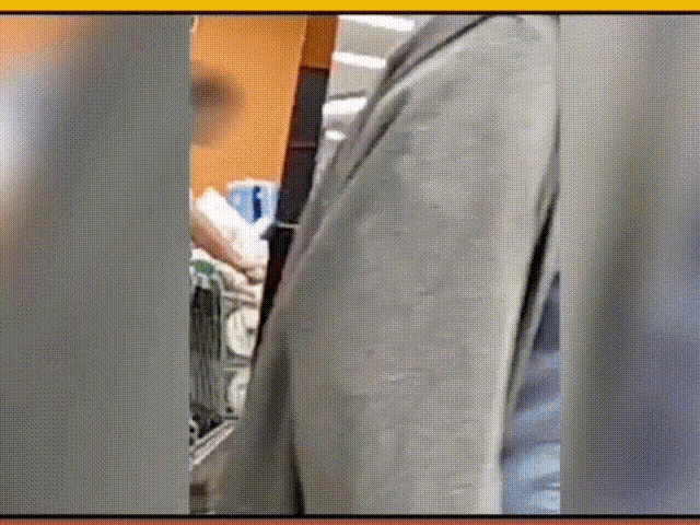 a man in a suit is standing in front of a shopping cart in a store