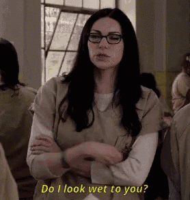 a woman wearing glasses is standing with her arms crossed and says `` do i look wet to you ? ''