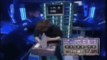a man is sitting at a table in front of a screen that says 00:00