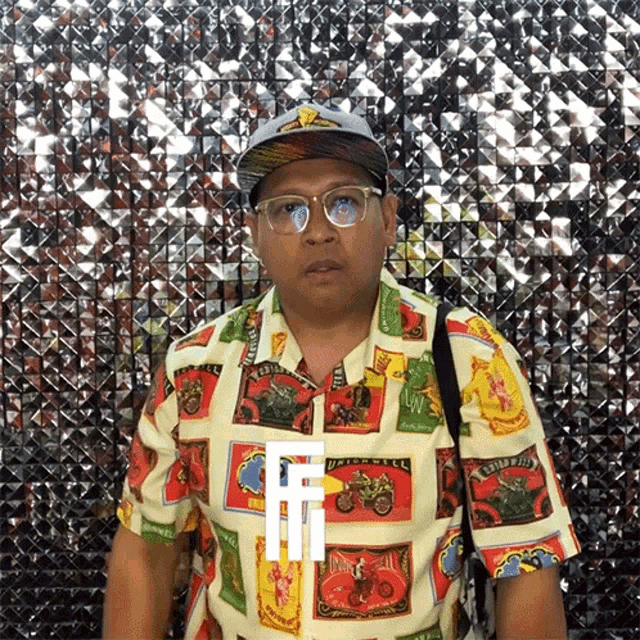 a man wearing a hat and glasses is standing in front of a shiny wall