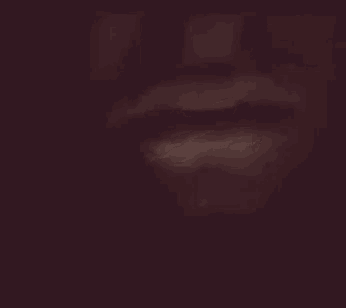 a blurry picture of a woman 's mouth with a dark background .