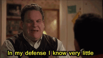 a man is talking to another man in a living room and says `` in my defense i know very little '' .