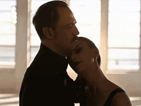 a man and a woman are kissing in front of a window