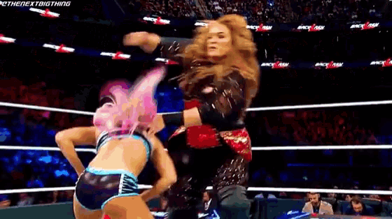 two women are wrestling in a ring with a crowd watching