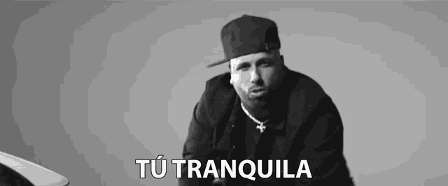 a black and white photo of a man wearing a hat and a jacket with the words tu tranquila above him