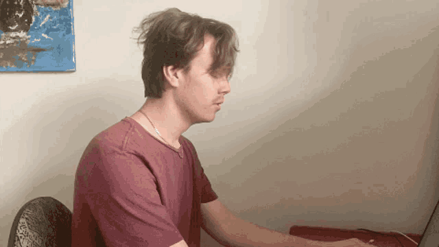 a man in a pink shirt is sitting at a desk with a laptop