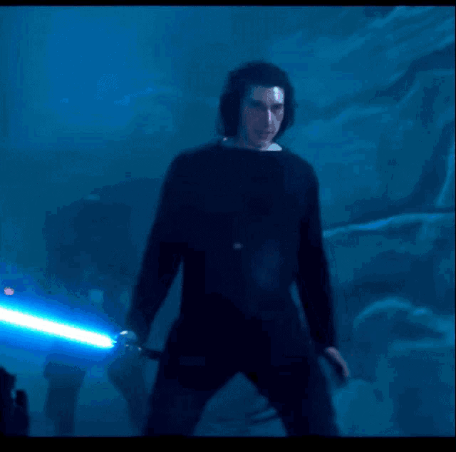 a man is holding a light saber in a dark room