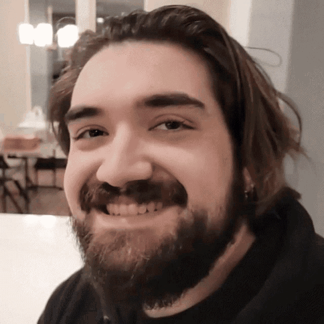a man with a beard is smiling and looking at the camera