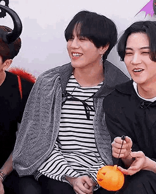 a group of young men are sitting next to each other and laughing while holding a pumpkin .