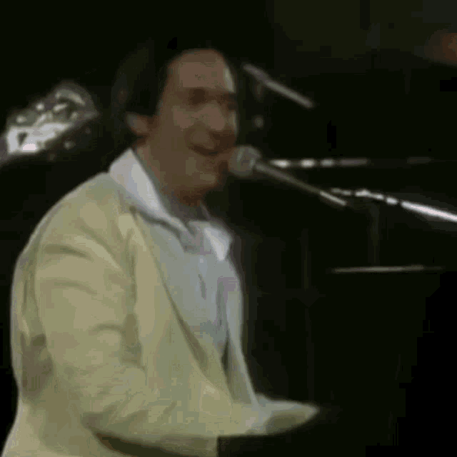 a man is singing into a microphone while playing a piano .