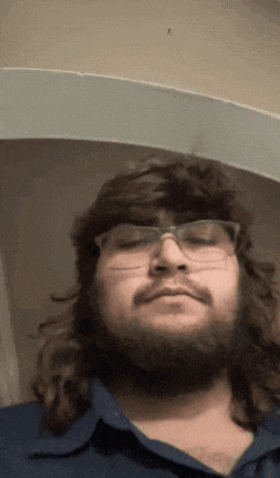 a man with long hair and glasses looks down at something