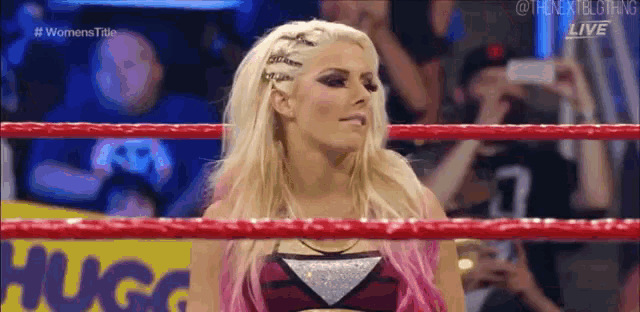 a woman is standing in the middle of a wrestling ring looking at the camera .
