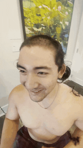 a man without a shirt is smiling in front of a picture