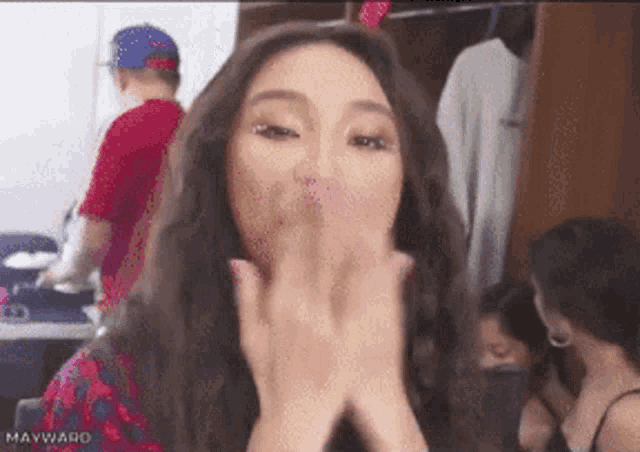 a woman blowing a kiss with the name mayward on the bottom right