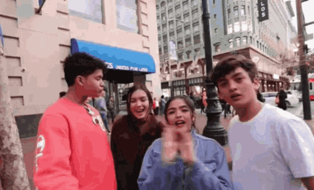 a group of people standing on a street in front of a store that says ' dresses for life '