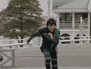a man in a green and black suit is running on a bridge