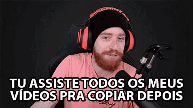 a man with a beard wearing headphones and a microphone says tu assiste todos os meus videos pra copiar