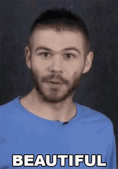 a man with a beard is wearing a blue shirt and making a face .