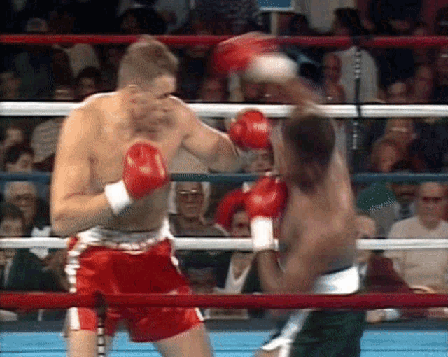 two men are boxing in a ring and one of them is wearing red shorts