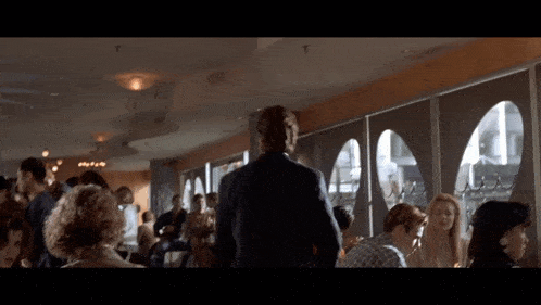a man in a suit stands in front of a crowd of people in a restaurant