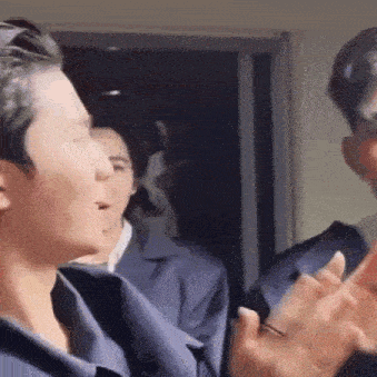 a group of men are standing next to each other in a room and clapping their hands .