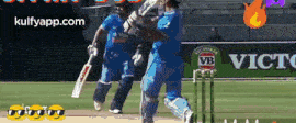 a cricket game is being played in front of a banner for victoria