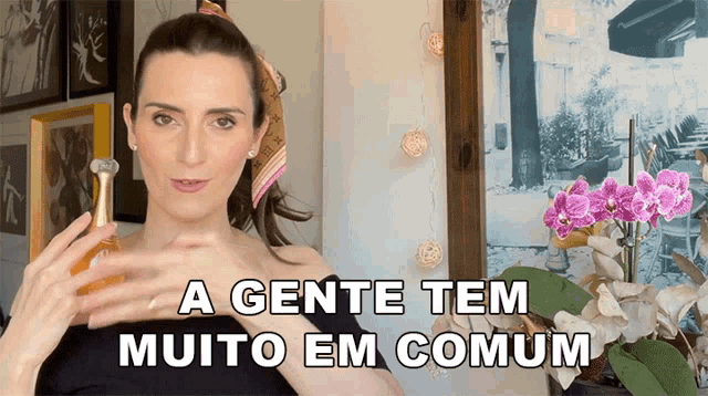a woman holding a bottle of perfume with the words a gente tem muito em comum