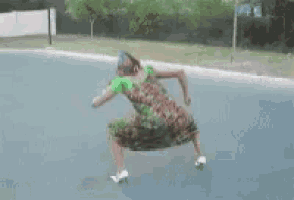 a woman in a green and red dress is dancing on a street