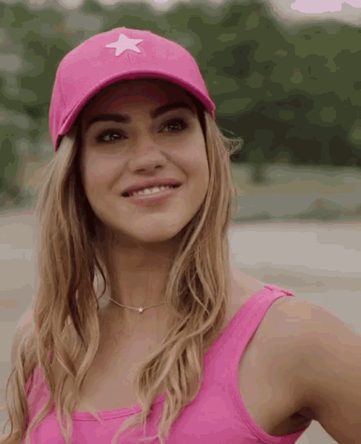 a woman wearing a pink hat with a white star on it smiles