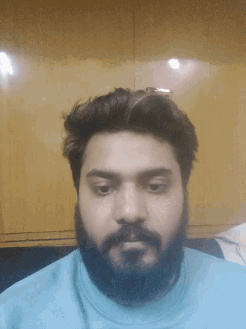 a man with a beard is wearing a blue shirt and looking at the camera