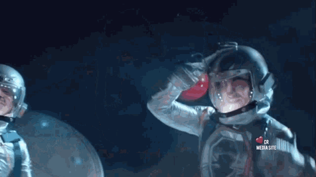 a man in a space suit is saluting in front of a sign that says media site
