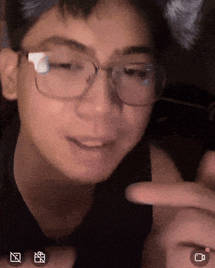 a close up of a person wearing glasses with a camera icon in the lower right corner