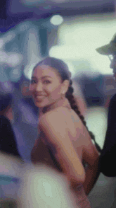 a woman in a dress is smiling and looking at the camera while standing next to a man in a hat .