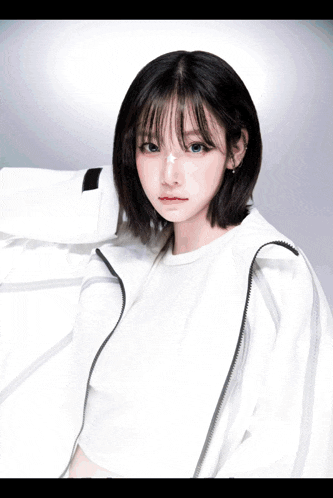 a girl wearing a white jacket and a white t-shirt looks at the camera