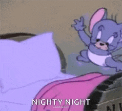 a cartoon mouse is sitting on top of a bed with a purple blanket .