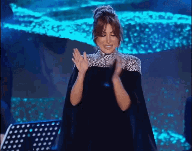 a woman in a black cape stands on a stage