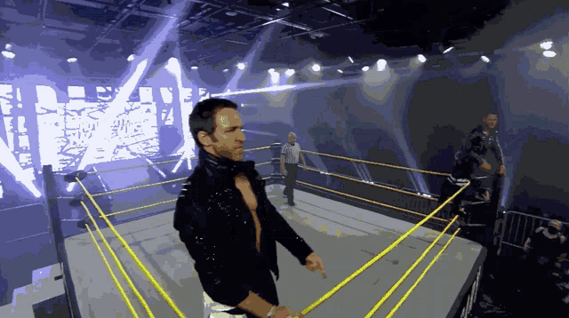 a wrestler stands in a wrestling ring with a large screen behind him that says wrestling