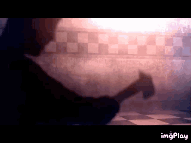 a person is holding a hammer in front of a checkered floor .