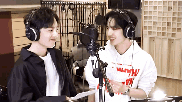 two young men wearing headphones and a sweatshirt that says " nlw " are standing in front of a microphone