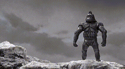 a black and white photo of a statue of a gorilla standing on top of a rock .