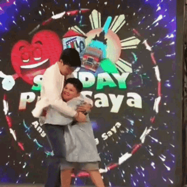 a man is hugging a little boy in front of a screen that says ' sday p saya '