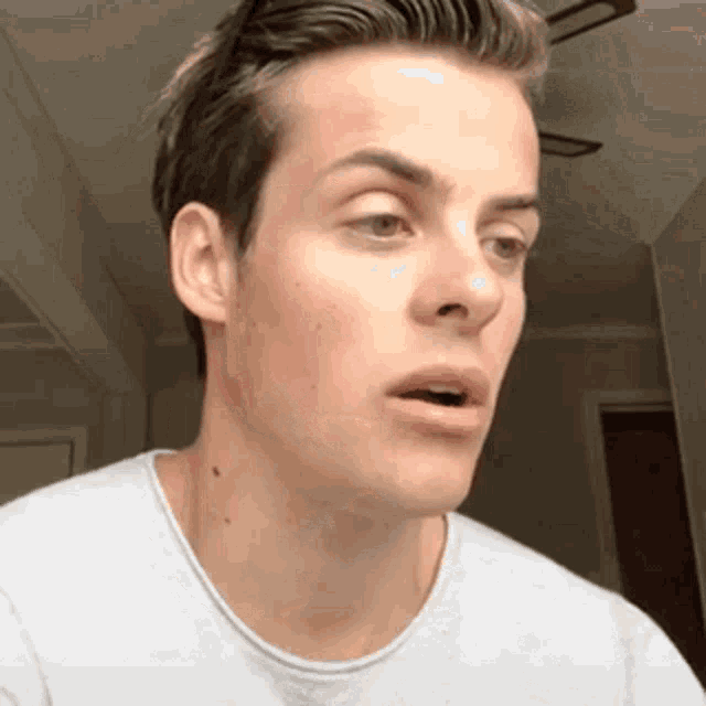 a close up of a man 's face with his mouth open and a ceiling fan in the background .