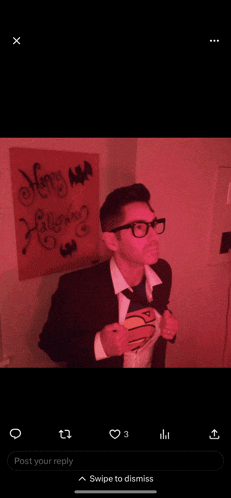 a man in a superman costume is in front of a sign that says happy halloween