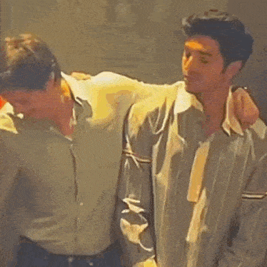 two men are standing next to each other and hugging each other in a room .