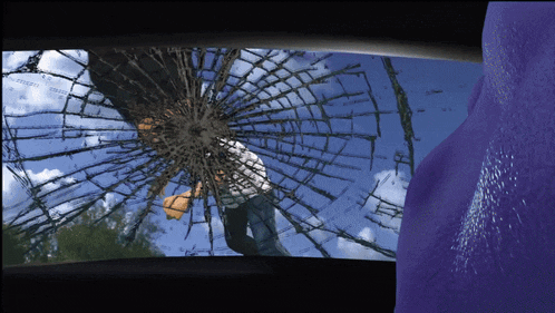 a man is looking through a broken glass window
