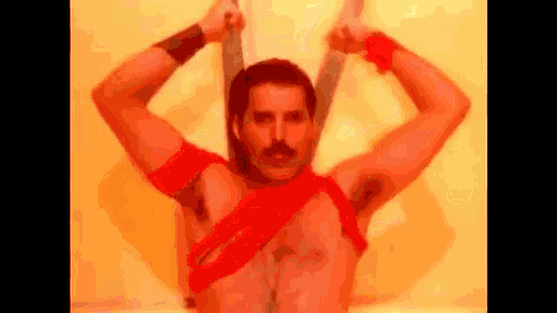 a shirtless man with a mustache is holding a pair of swords in his hands .