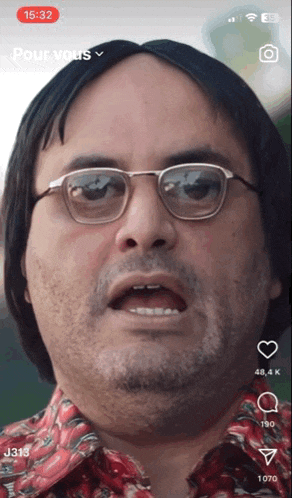 a man wearing glasses and a red shirt is on a cell phone screen