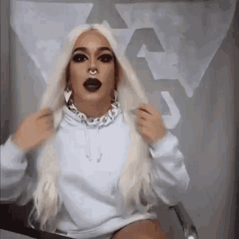 a woman with long white hair and a nose ring is wearing a white hoodie and earrings .