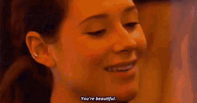 a woman is smiling and saying `` you 're beautiful '' in a close up of her face .