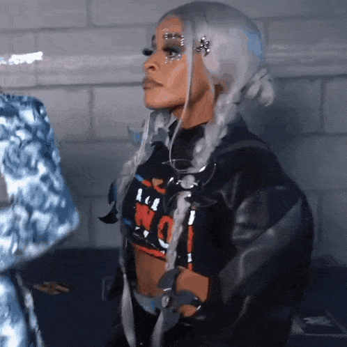 a woman with white hair and rhinestones on her face is wearing a black jacket